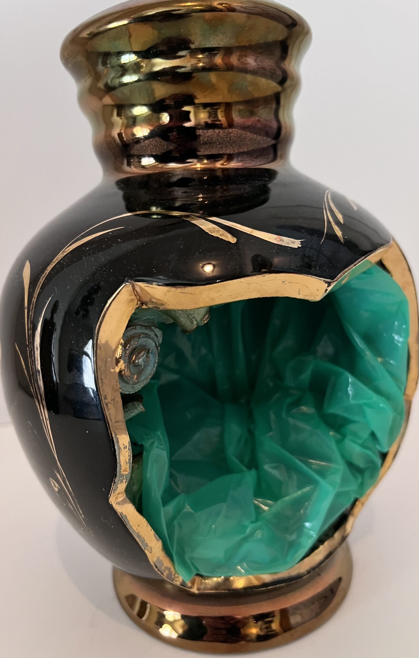 Poème plastique de Fernando Arrabal. Petit vase noir et doré brisé, transformé en objet artistique au cœur vert en plastique froissé.