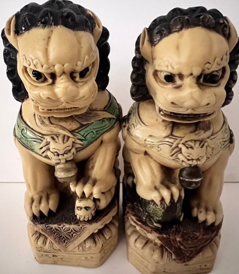 Deux statuettes sculptées représentant des lions gardiens stylisés chinois, placées côte à côte sur un fond neutre.
