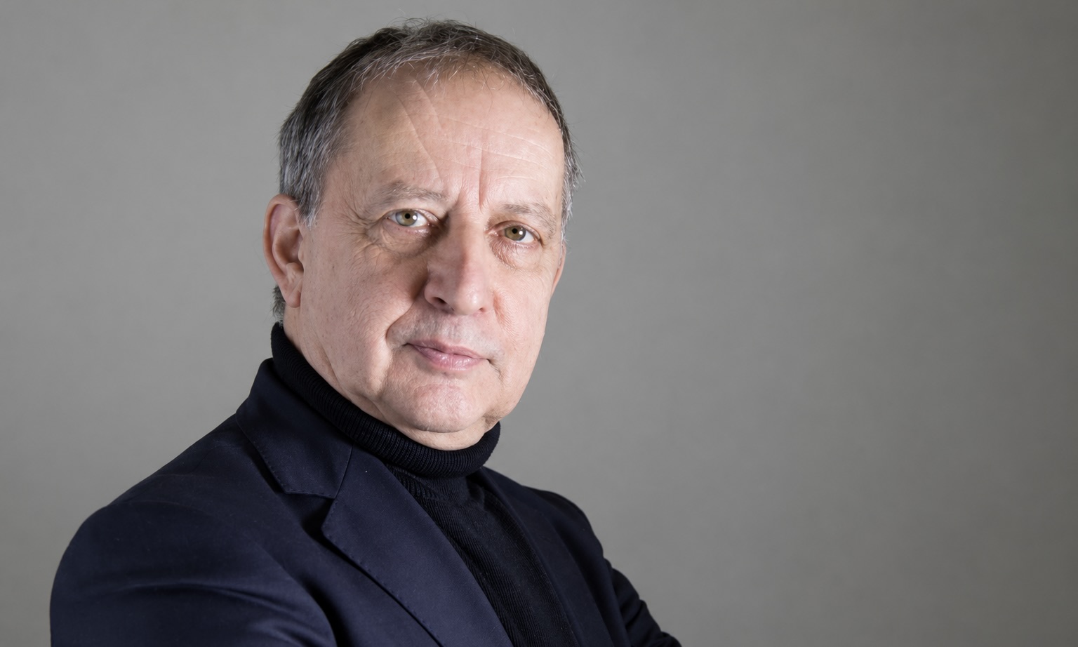 L’essayiste et professeur Norbert Hillaire pose devant un fond gris.