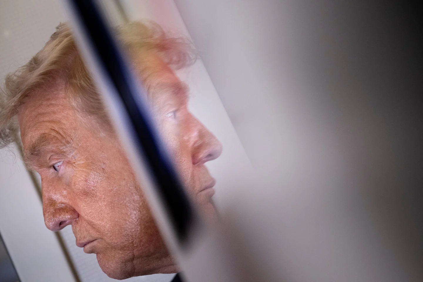Le président Donald Trump et son reflet lors d’un point de presse à bord d’Air Force One après son départ de Pékin, le 15 mai 2026.