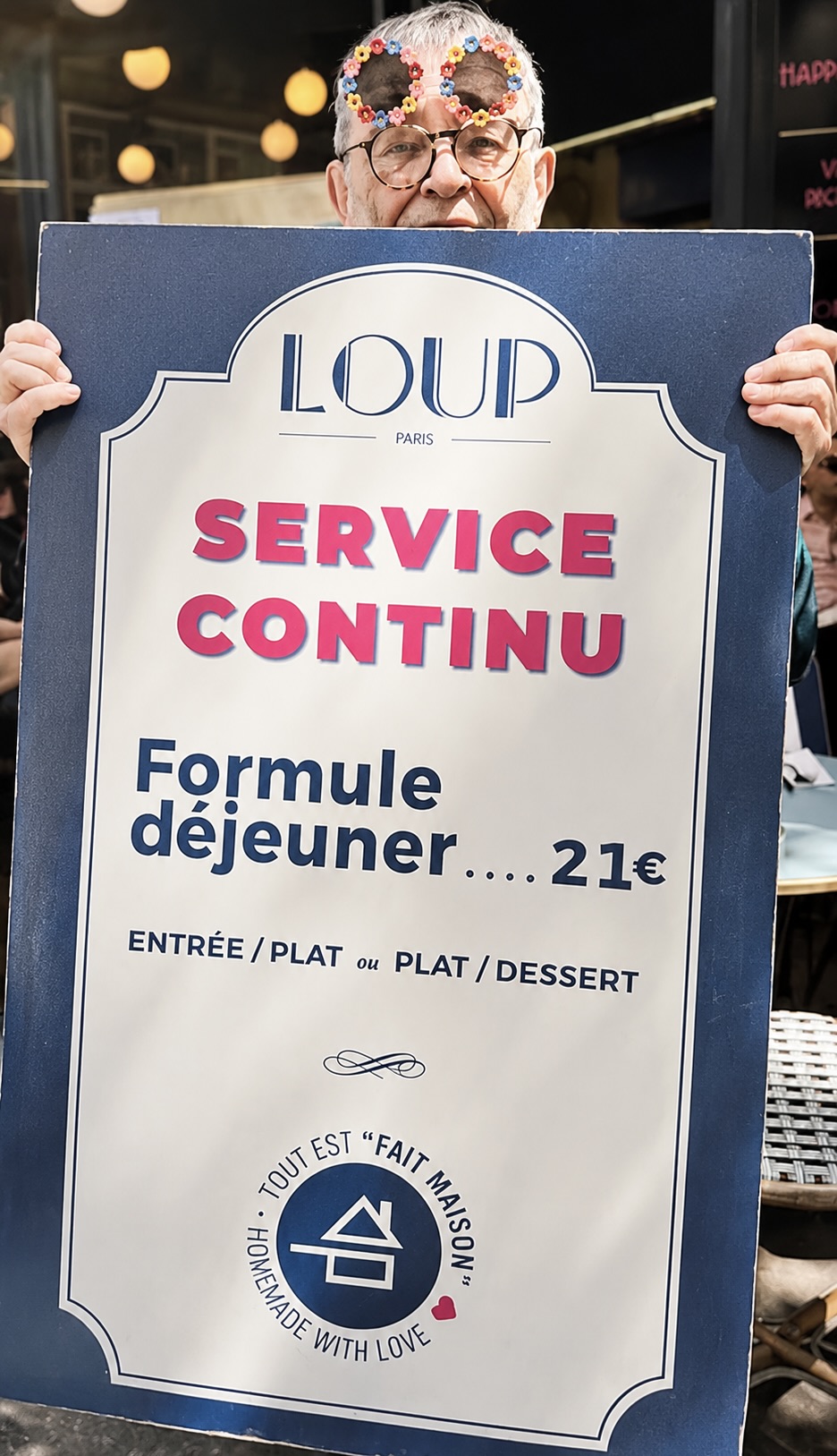 Fernando Arrabal au restaurant Loup, il tient la pancarte du restaurant.