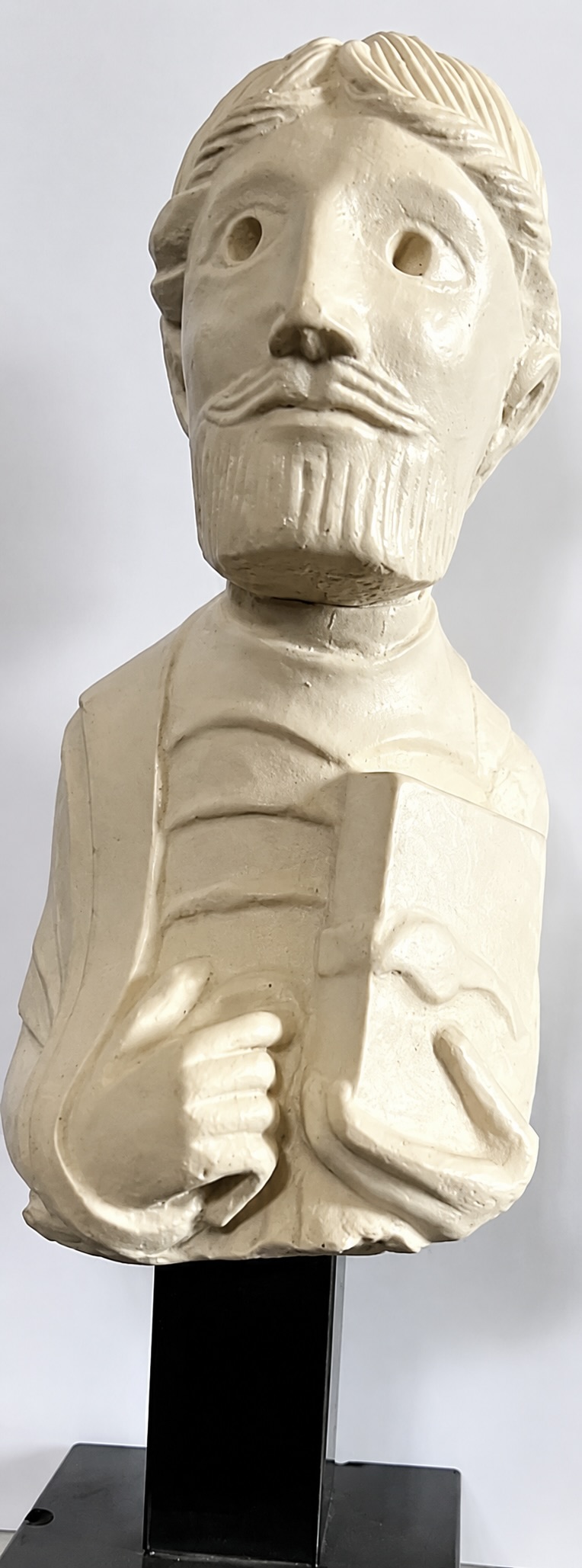 Buste sculpté représentant un personnage barbu tenant un livre, monté sur un socle noir.