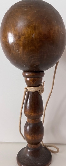 Bilboquet ancien en bois tourné, composé d'une boule percée reliée à un manche par une corde.