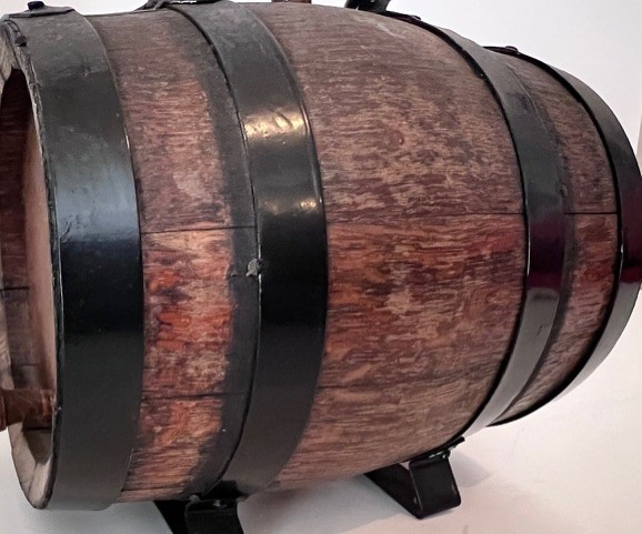 Petit tonneau décoratif en bois cerclé de métal noir, posé sur un support.