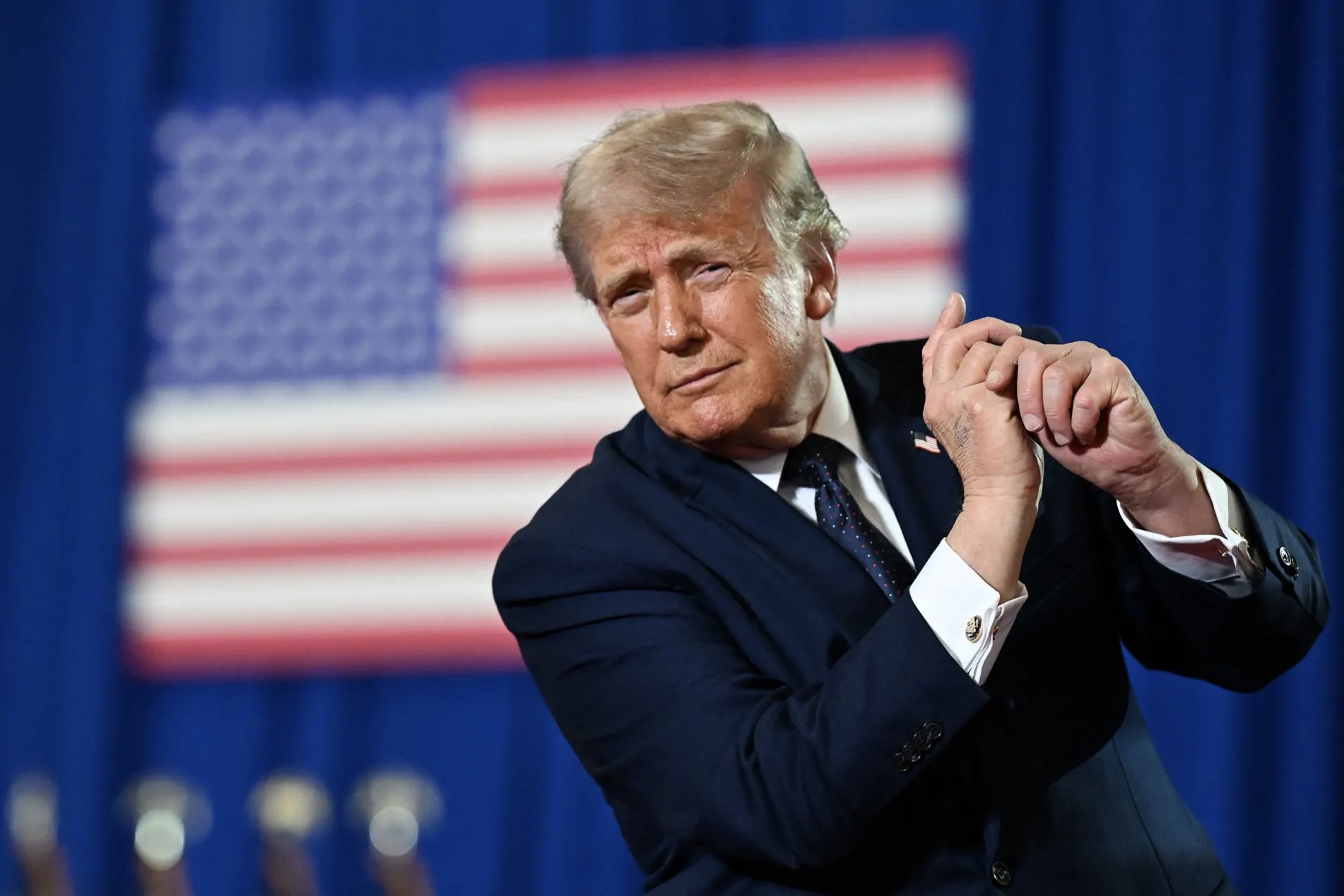 Le président américain Donald Trump, derrière lui on voit un drapeau des USA.