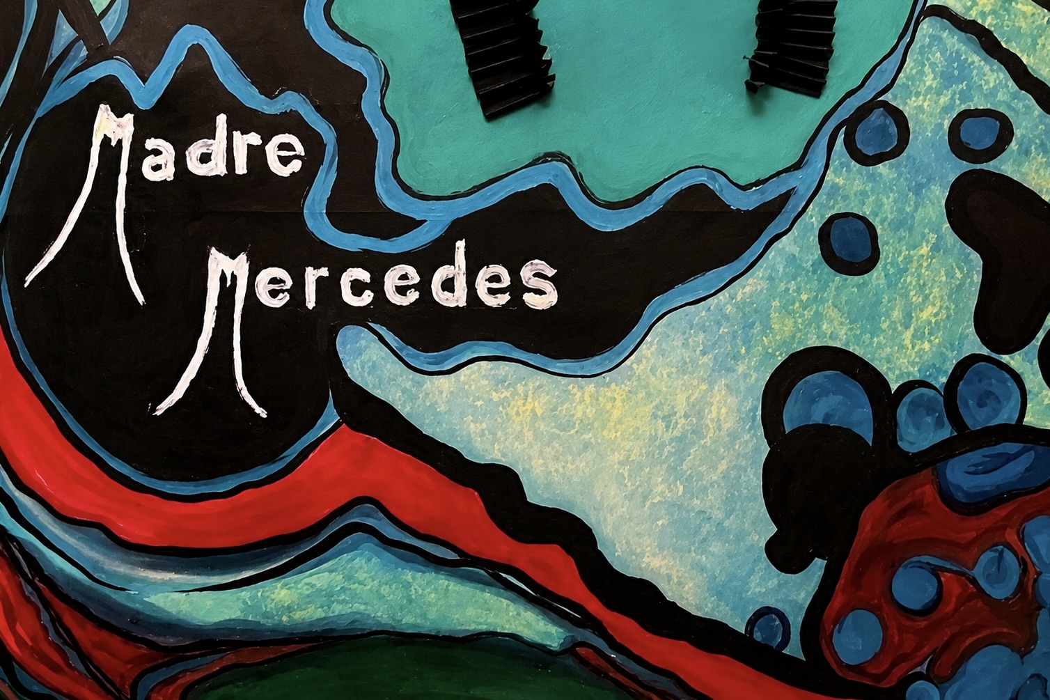 Une peinture abstraite aux formes organiques en noir, turquoise, bleu, rouge et vert, comportant les inscriptions « Madre Mercedes ».