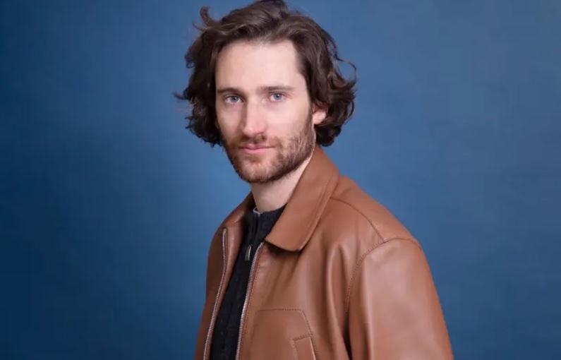 Portrait de l'écrivain François-Henri Désérable sur fond bleu.