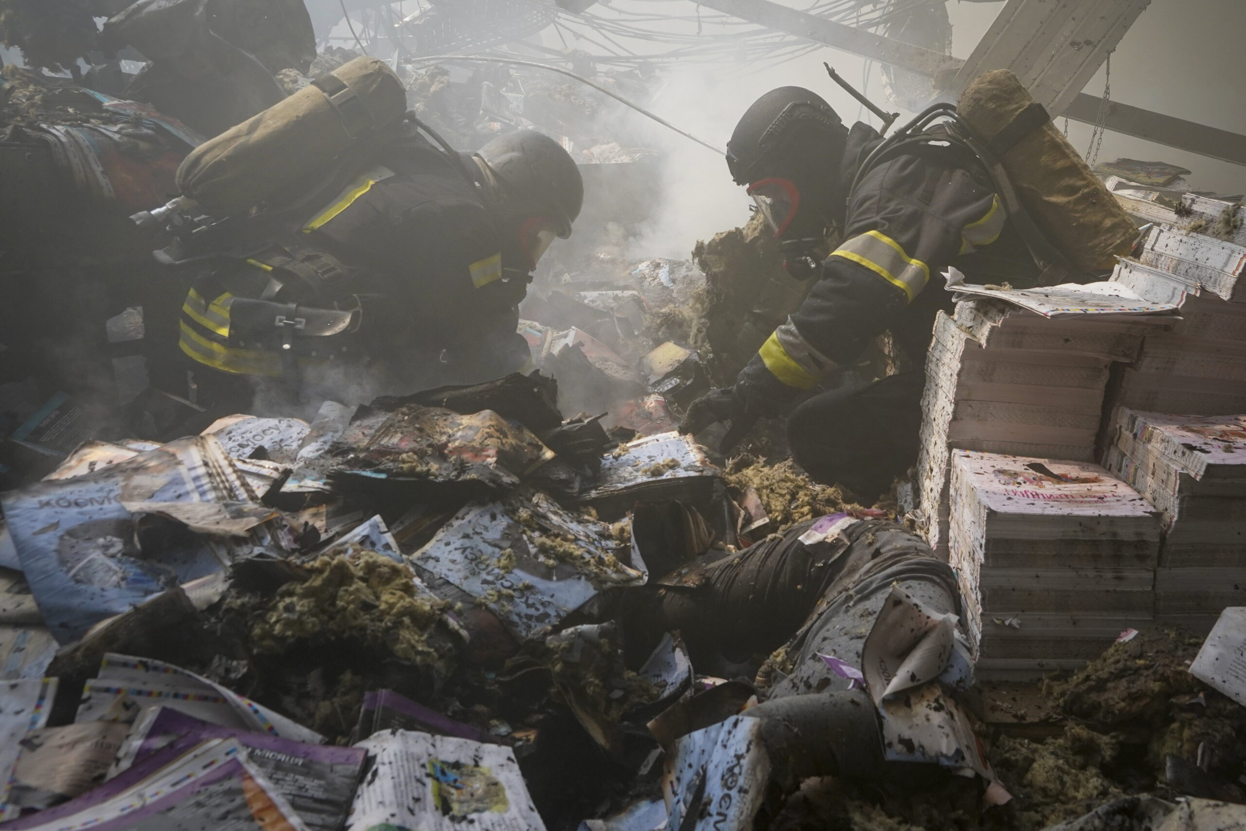 Bombardement russe de la plus grande imprimerie ukrainienne. On voit des pompiers au milieu de piles de livres carbonisés, il y a un cadavre sous les livres.