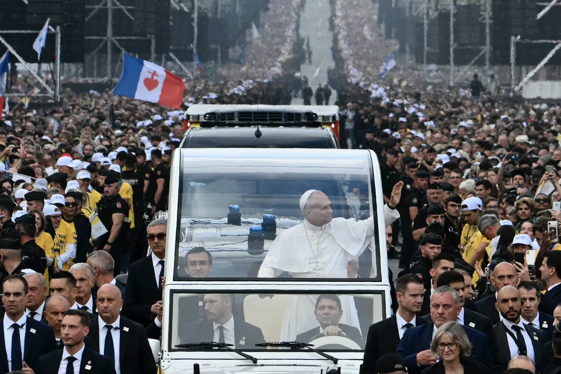 Le pape Léon XIV salue la foule depuis la papamobile sur les Champs-Élysées, en direction de la place de la Concorde